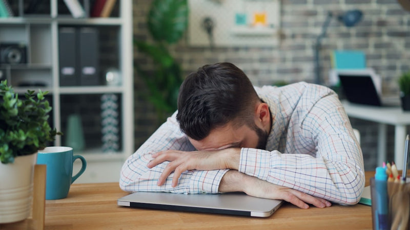 Tired worker slumped asleep on a laptop from poor ergonomics